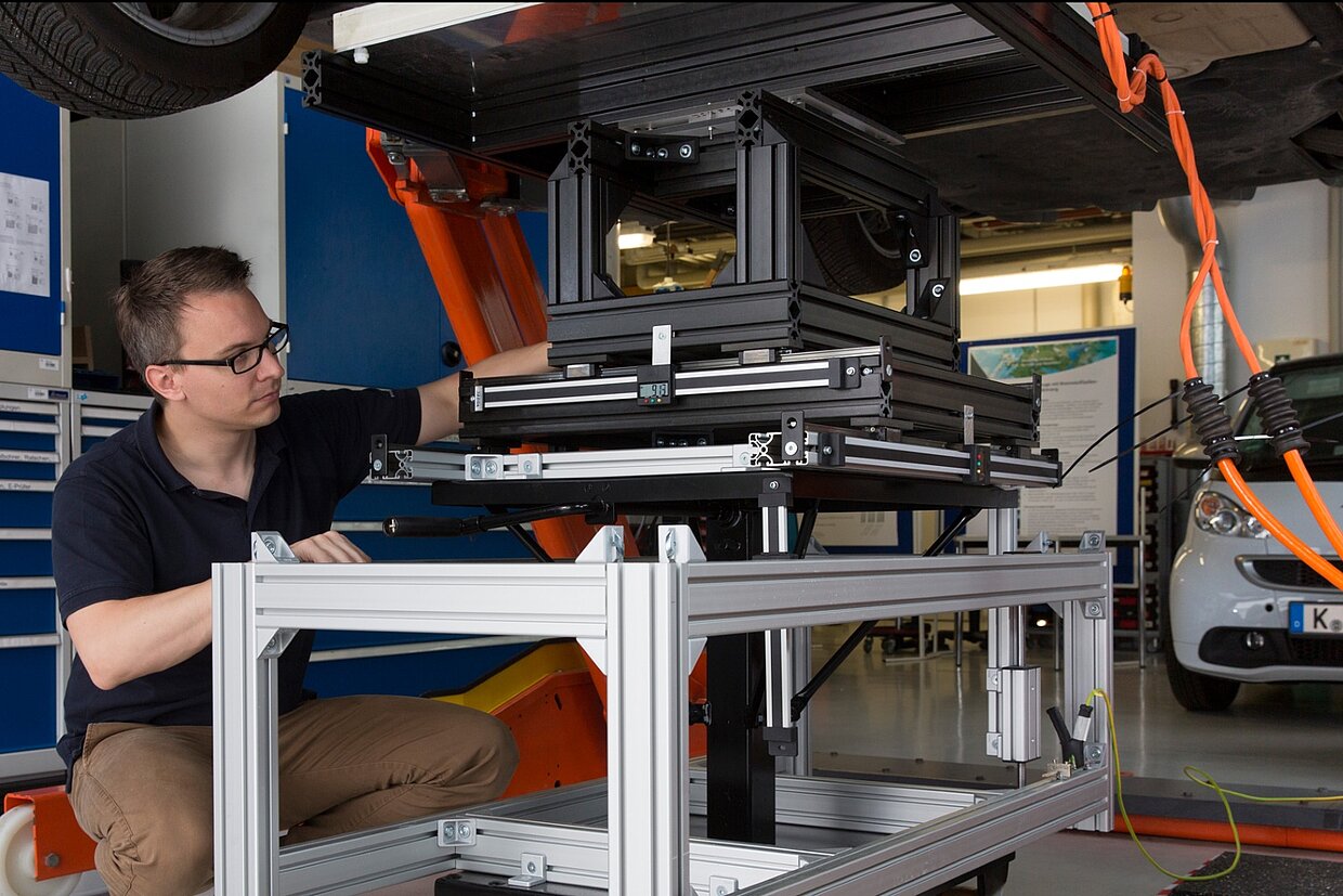 Induktives Schnelladesystem Ein Mitarbeiter arbeitet an einem induktiven Schnellladesystem.