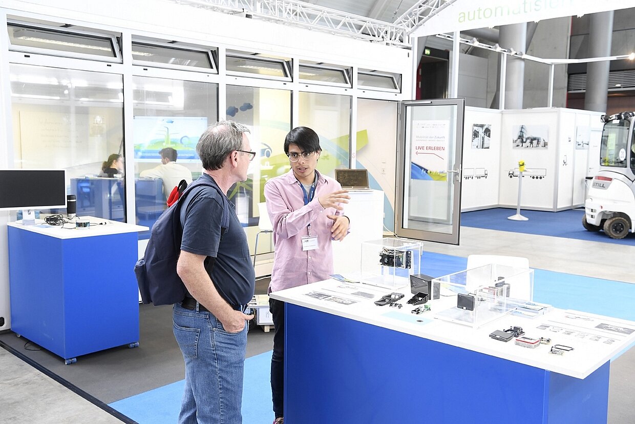 Zwei Personen unterhalten sich auf einem Messestand.