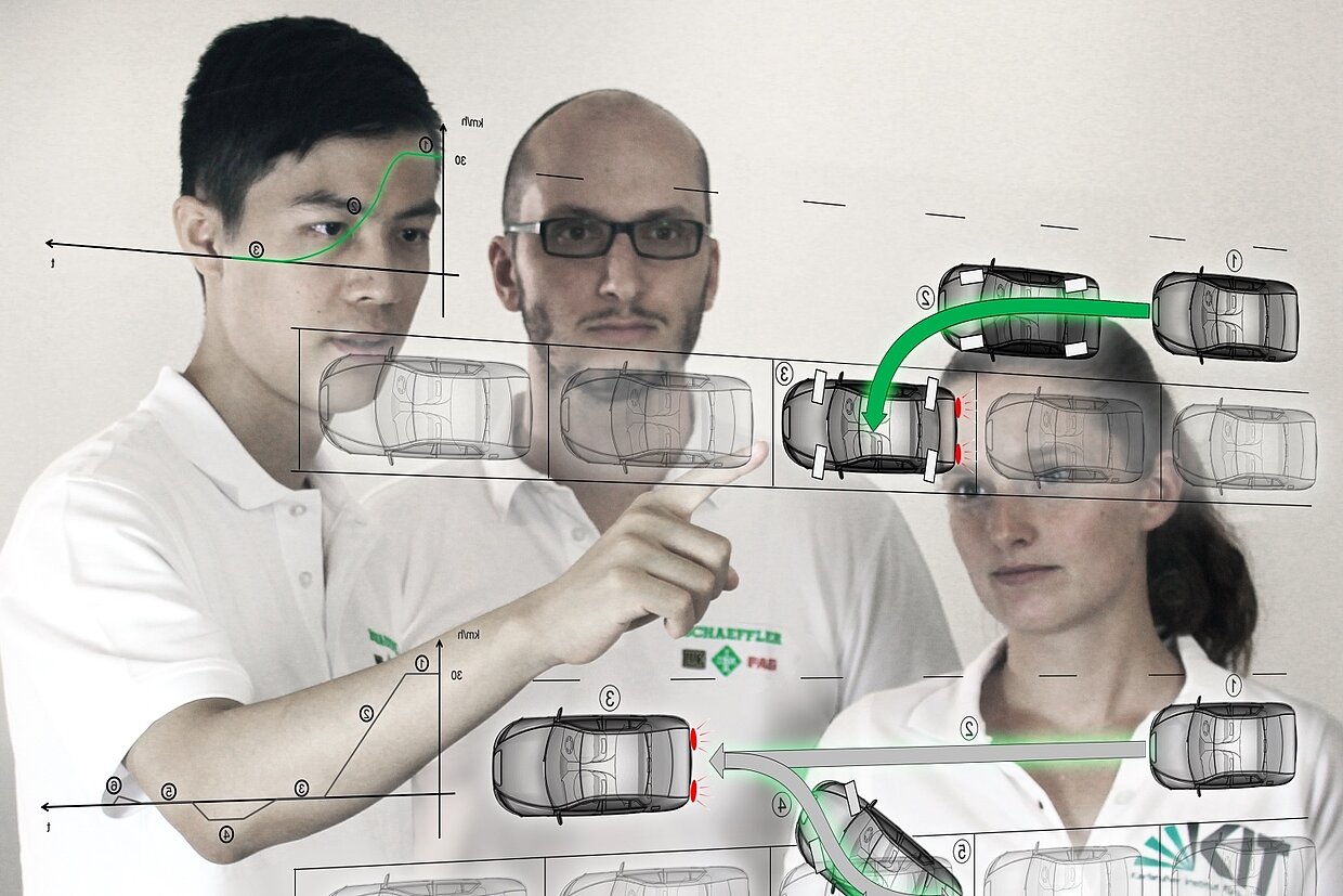 Zwei Männer und eine Frau stehen hinter einer durchsichtigen, virtuellen Projektionswand auf der Autos zu sehen sind.