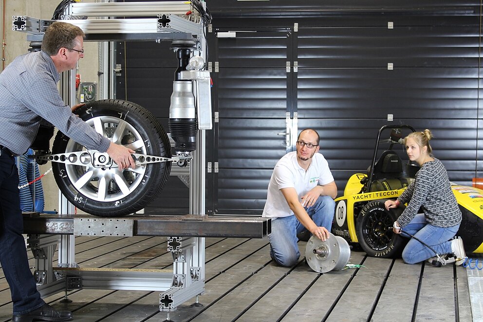 Zwei Männer und eine Frau arbeiten an einem Versuchsaufbau zum radselektiven Antrieb.