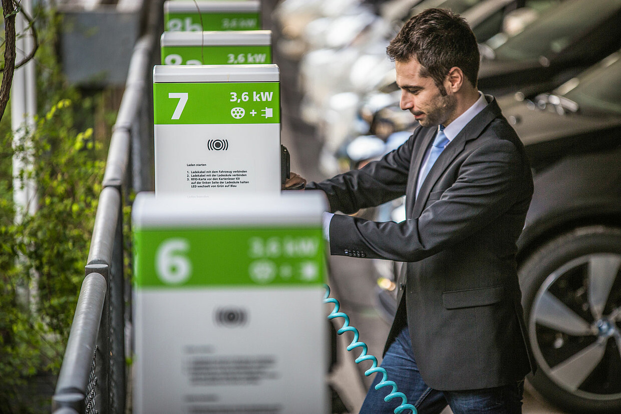 Ladesäule im Einsatz Ein Mann steht an einer Ladesäule mit der Nummerierung 7.