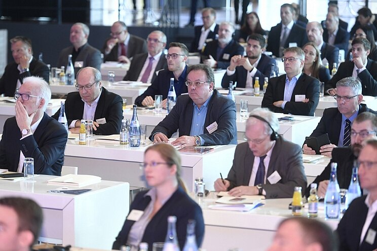 Blick auf Teilnehmende bei einer Veranstaltung, die an ihren Plätzen sitzen.