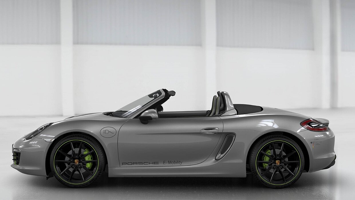 Ein silberner Porsche Boxster steht vor einer weißen Wand.