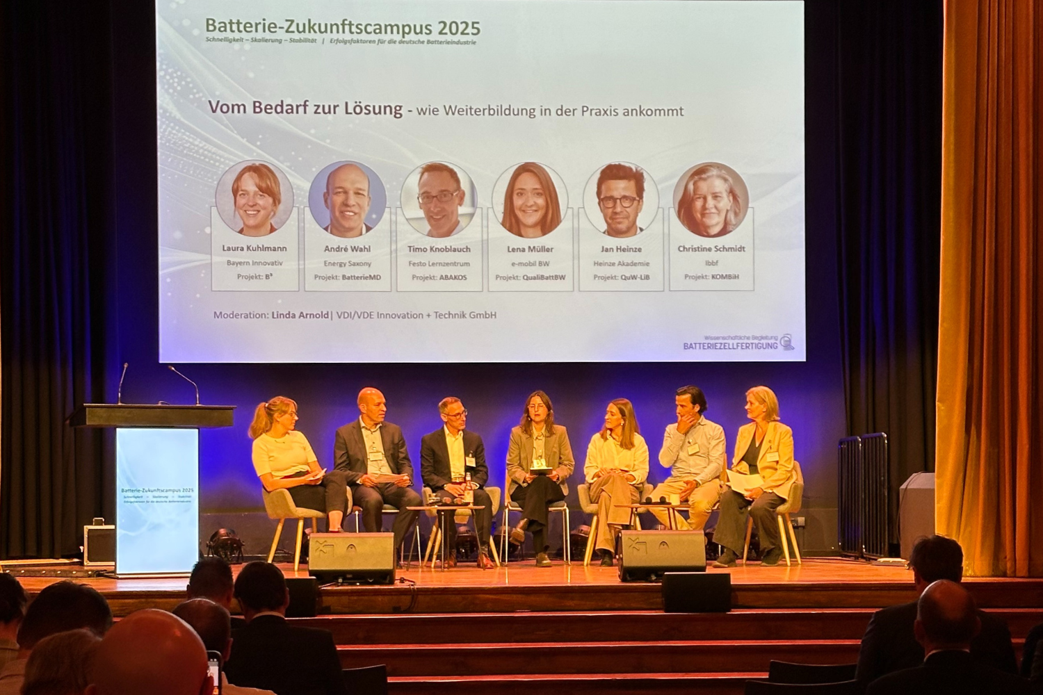 Sechs Vertreterinnen und Vertreter der Weiterbildungsverbünde Batterie und eine Moderatorin sitzen für ein Panel auf einer Bühne und diskutieren.